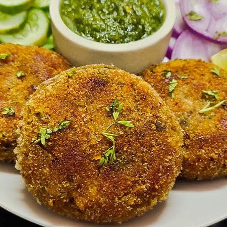 Delicious golden-brown cutlets kebabs, perfectly grilled and served on a plate with garnished herbs and a side of dipping sauce.